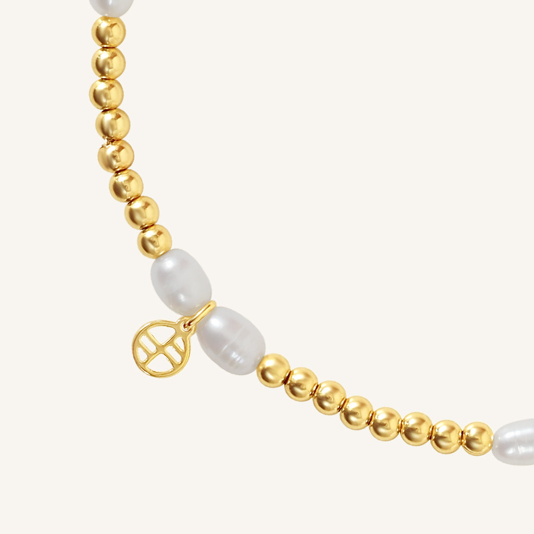 A coloured stretchy anklet with freshwater pearls and a small gold charm, displayed against a white background.