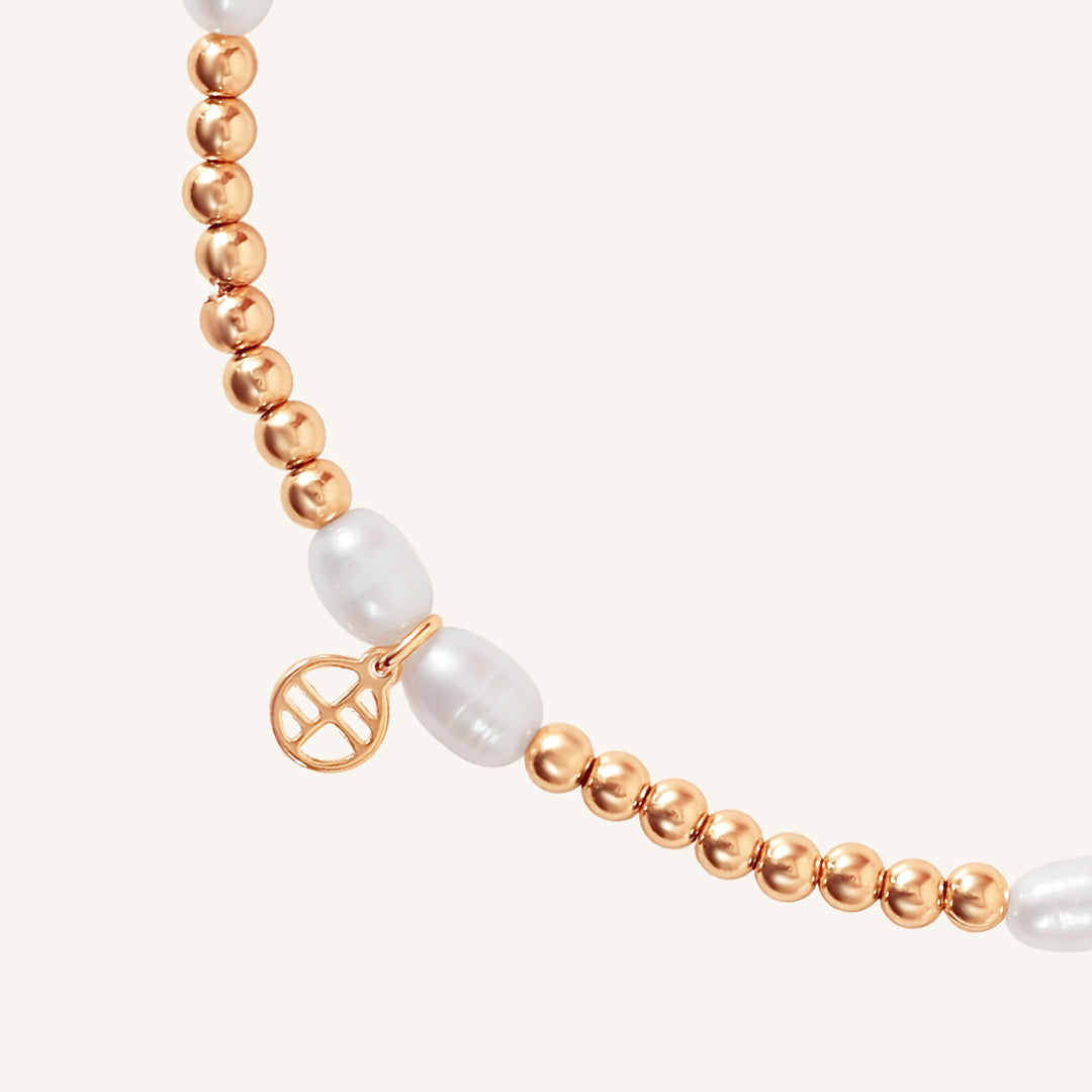 A coloured stretchy anklet with freshwater pearls and a small gold charm, displayed against a white background.