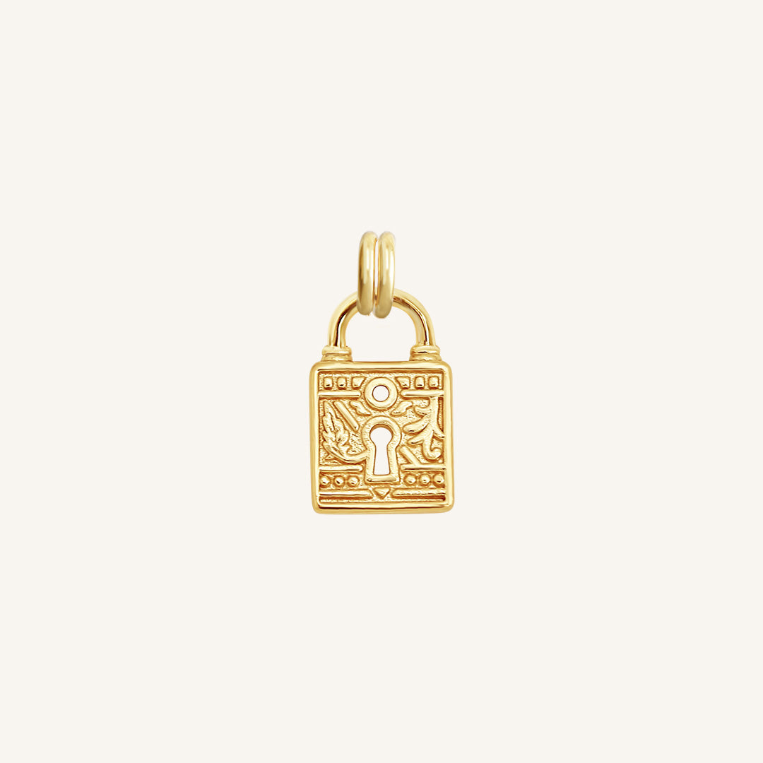 A gold-colored charm in the shape of a keylock with intricate patterns.