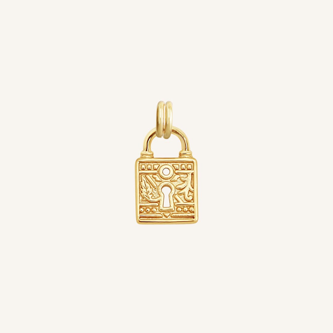 A gold-colored charm in the shape of a keylock with intricate patterns.