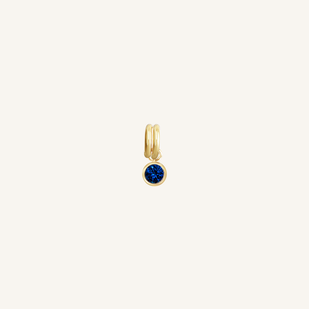 Gold bezel-set blue sapphire cubic zirconia charm representing the September birthstone.