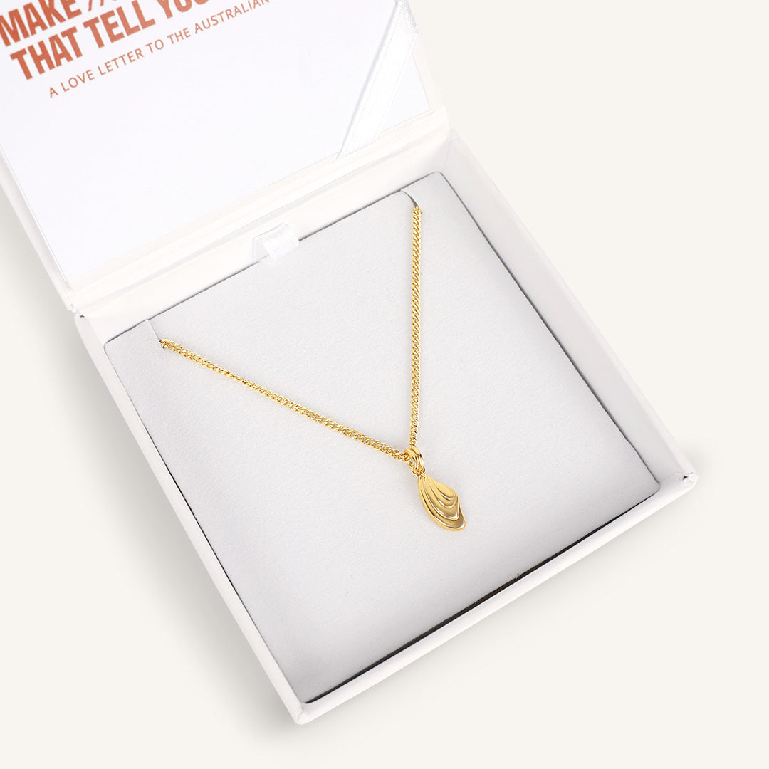 Gold necklace in a white box with text on a white background