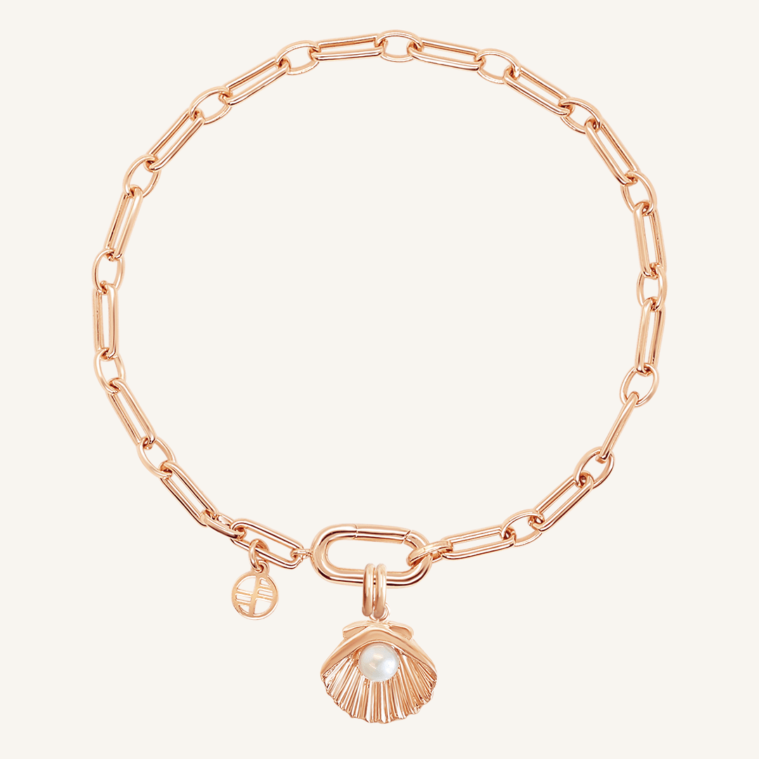 A rose-colored chain bracelet with a shell shaped charm with a pearl in the middle