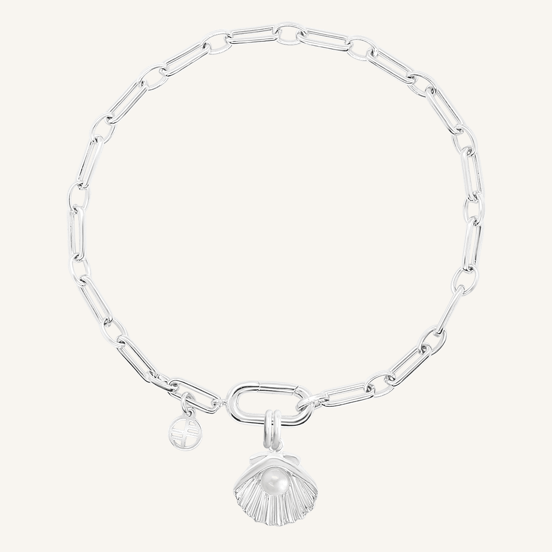 A silver-colored chain bracelet with a shell shaped charm with a pearl in the middle