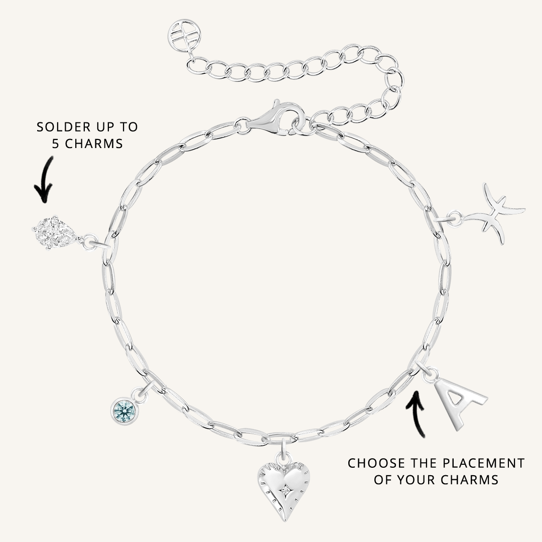 A silver-tone bracelet with paperclip links and multiple charms, including a heart, a star, and a letter, with an extender chain.