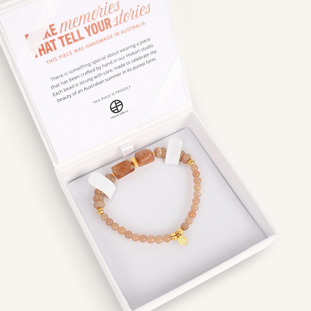 Beaded bracelet with gold heart charm in a box with product description