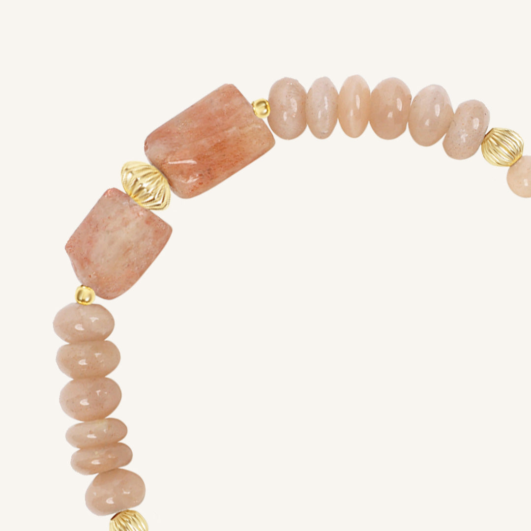 Bracelet with pink stone beads and gold accents on a white background