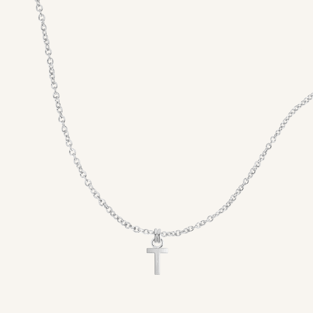 Silver necklace with a T pendant on a light gray background