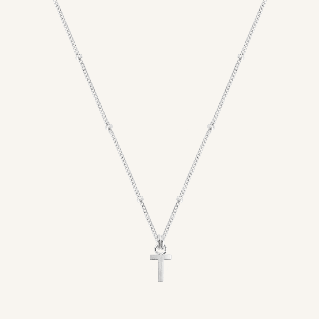 Silver necklace with a 'T' pendant on a light gray background