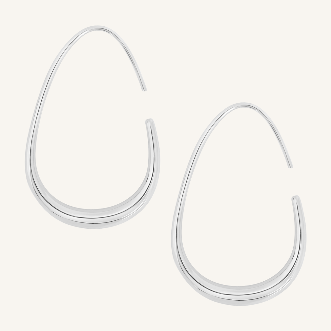A pair of silver-colored hoop earrings with a geometric design, displayed against a white background