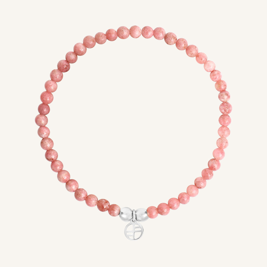 Pink beaded bracelet with a silver charm on a white background