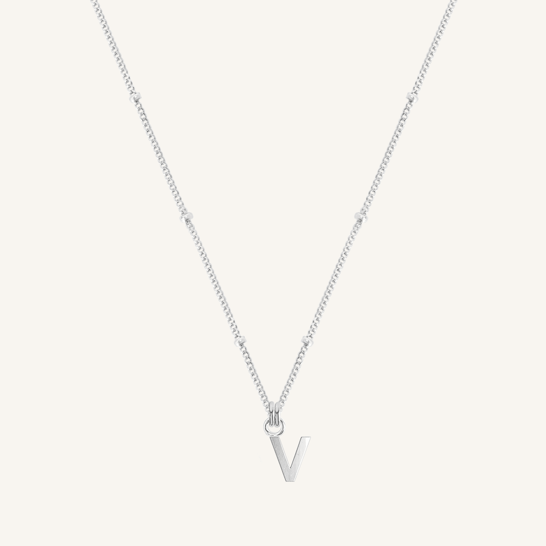 Silver necklace with a 'V' pendant on a light gray background