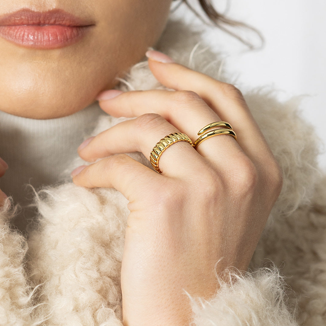 Close-up of a hand wearing gold rings with a soft background