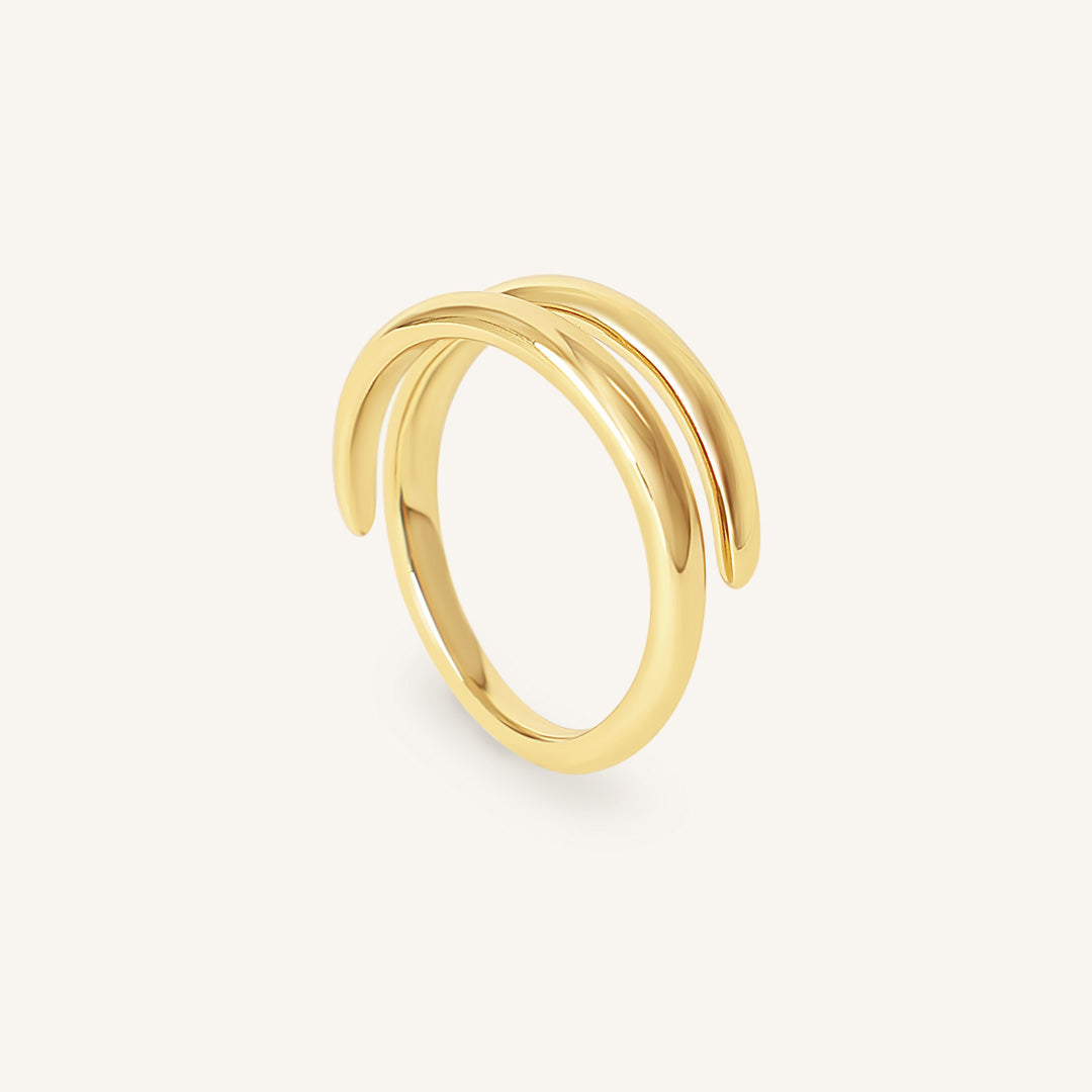 Gold ring with a twisted design on a light beige background