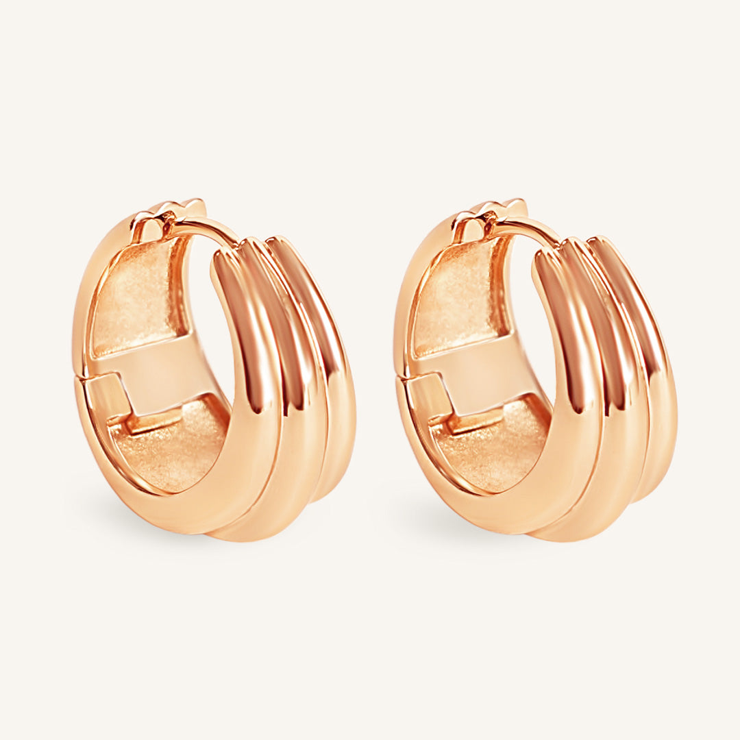 Rose gold hoop earrings on a light beige background