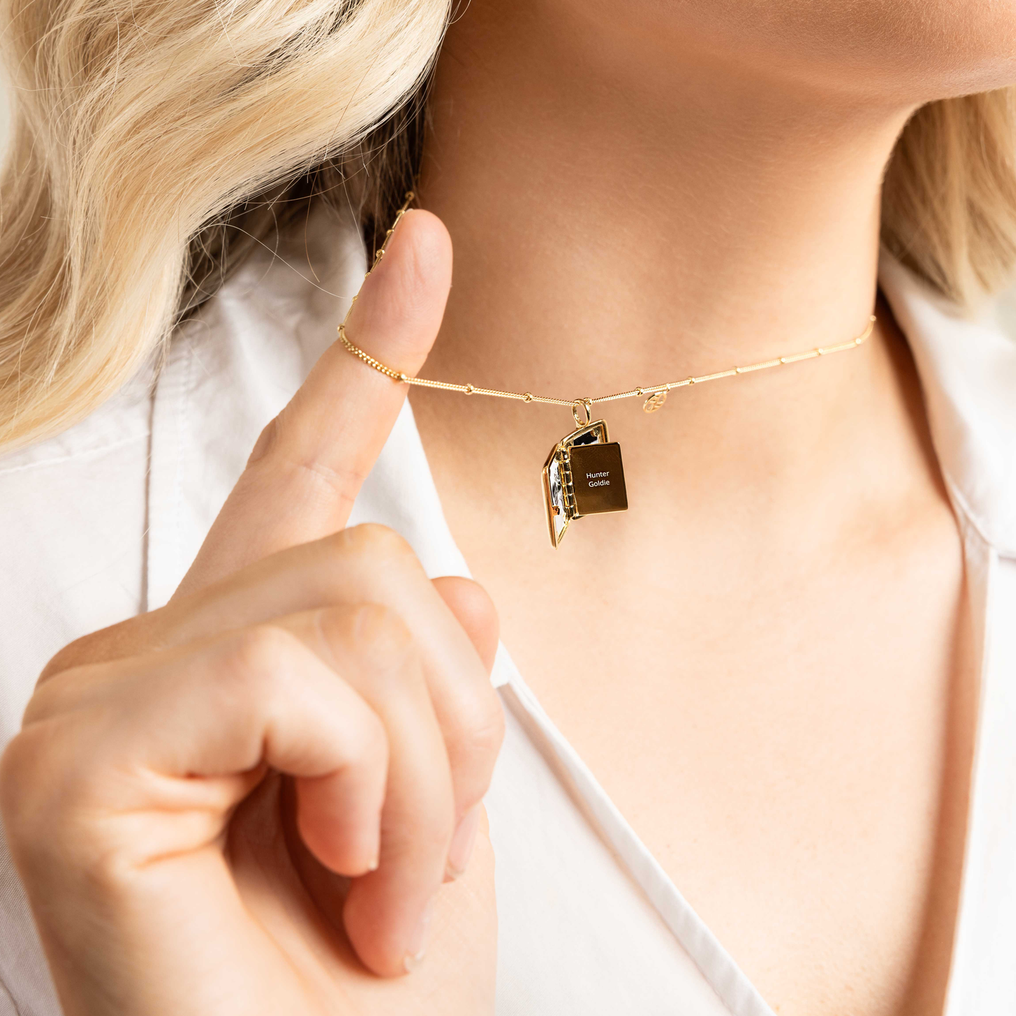 Gold locket on a chain, open to reveal a middle panel with engraving