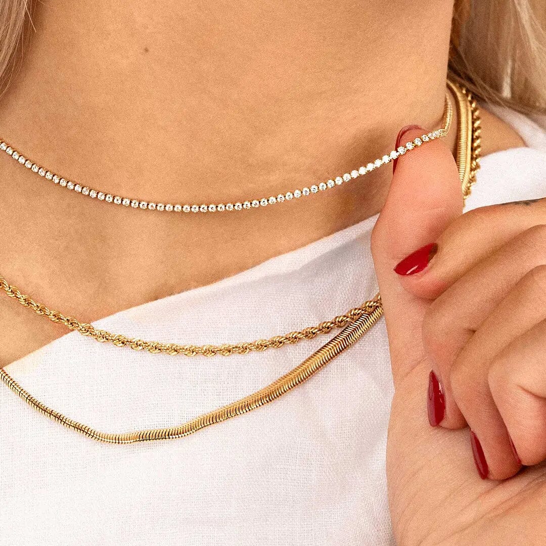 Close up on tennis chain necklace with gold metal tone, on models neck.