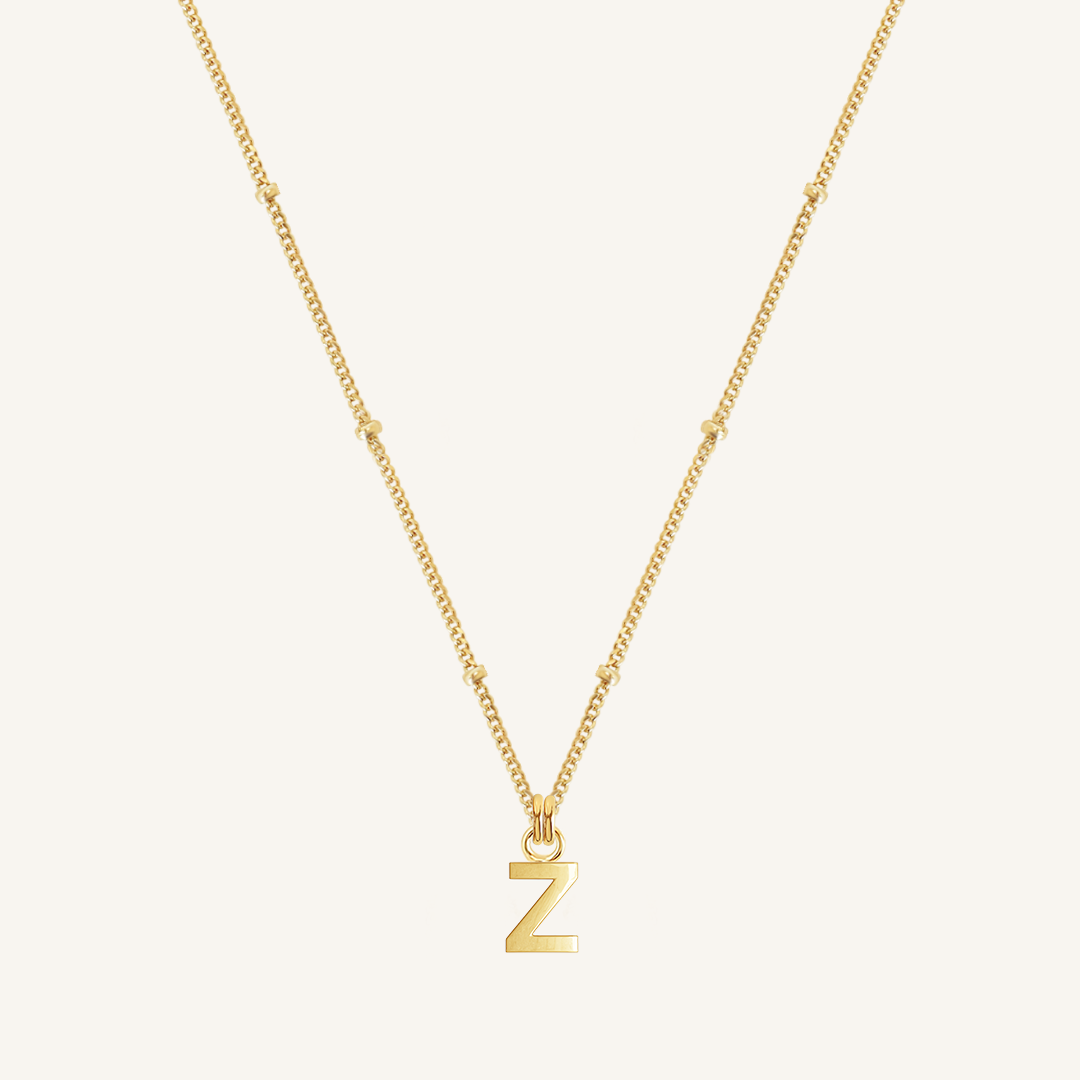 Gold necklace with a 'Z' pendant on a light beige background