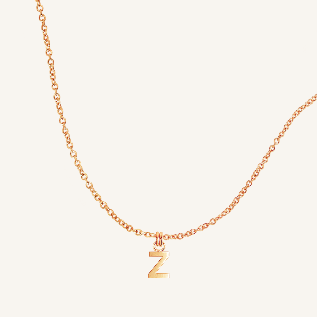 Rose gold necklace with a 'Z' pendant on a light beige background