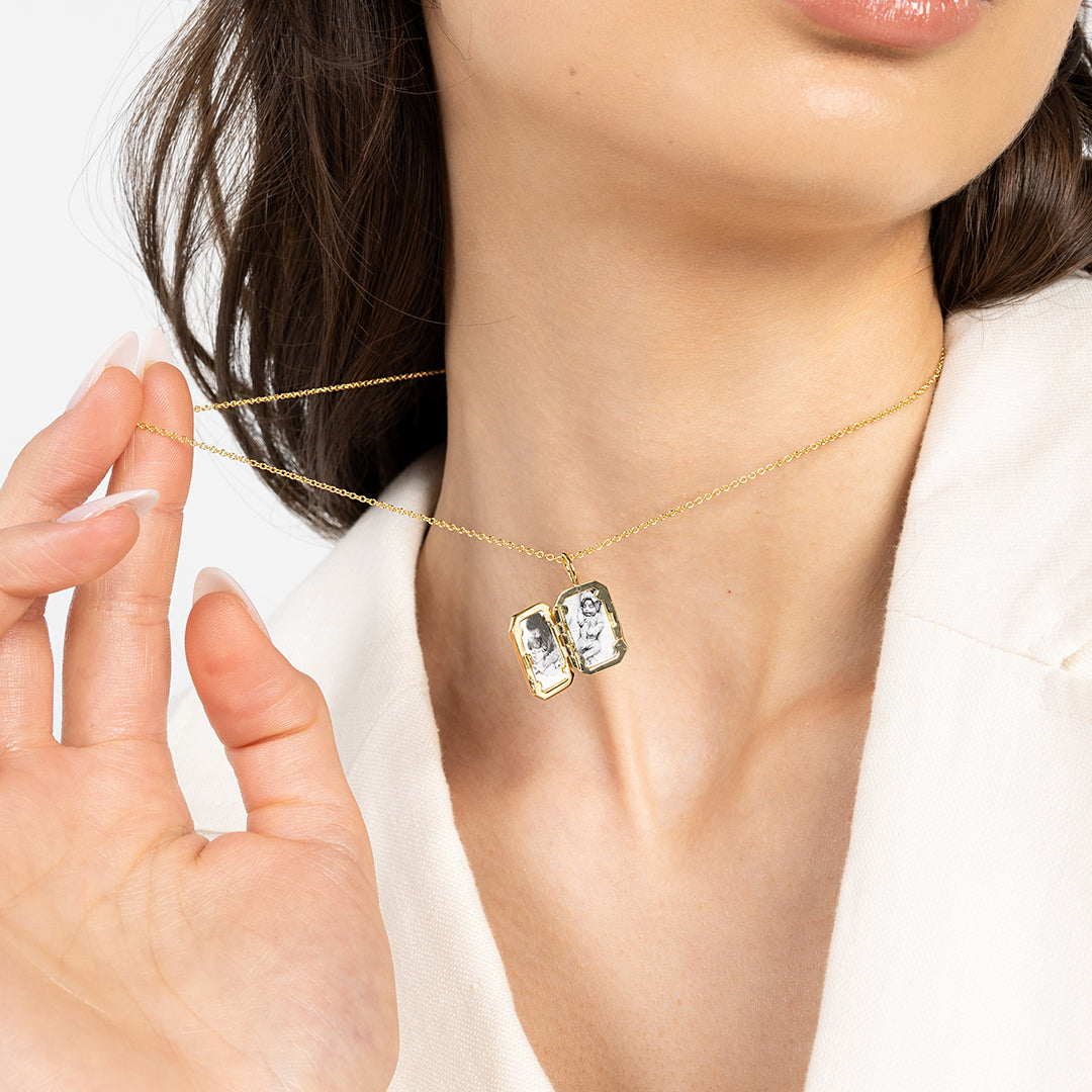 Gold bevel locket open showing photos, on chain, around neck