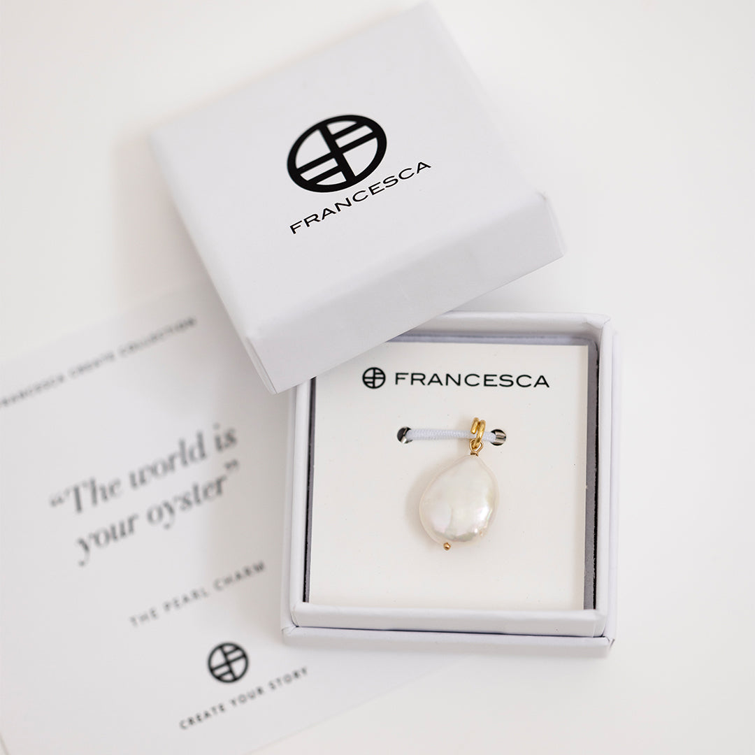 A medium sized pearl charm with gold findings, in white box