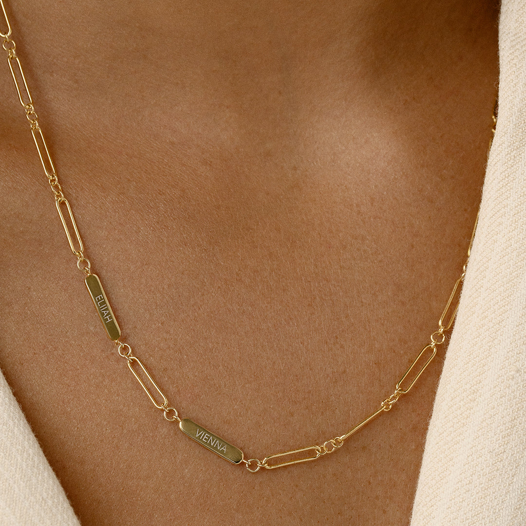 A gold chain necklace with two engraveable panels close up around the neck