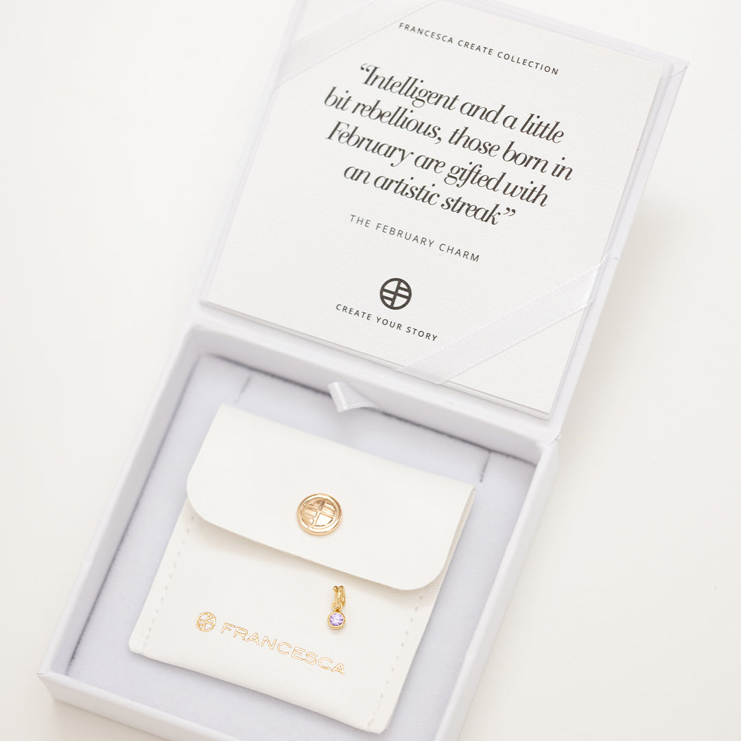Round gold charm with bezel-set amethyst cubic zirconia representing the February birthstone in white box.