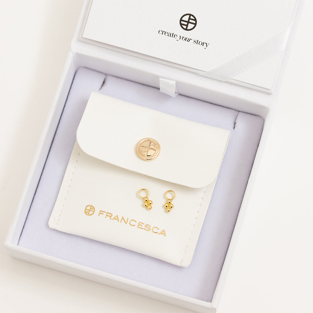 A set of two hoop charm earrings, featuring petite bobble details, attached to hoops, displayed in white box