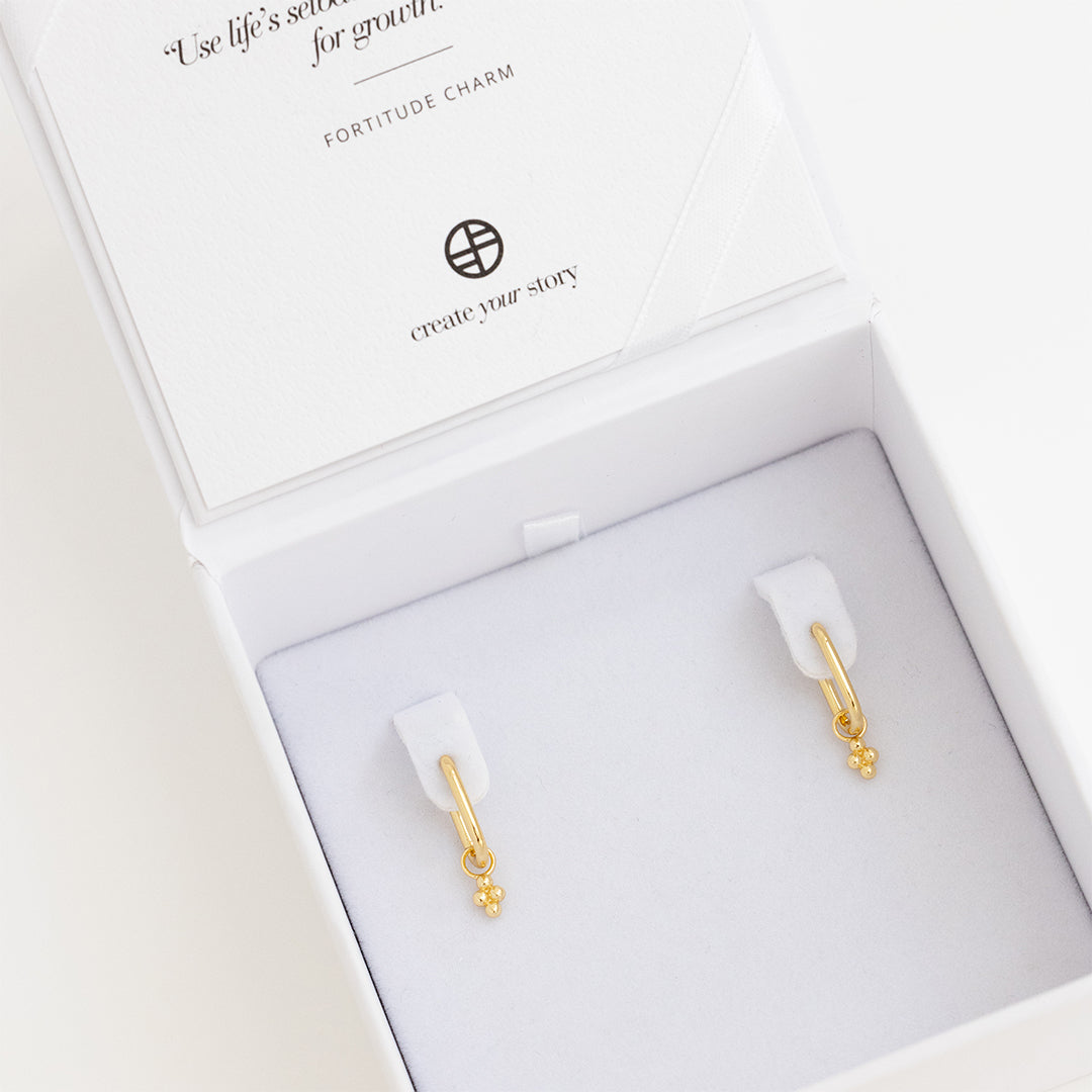A pair of gold-tone rectangle hoop earrings with petite bobble details, displayed in white box