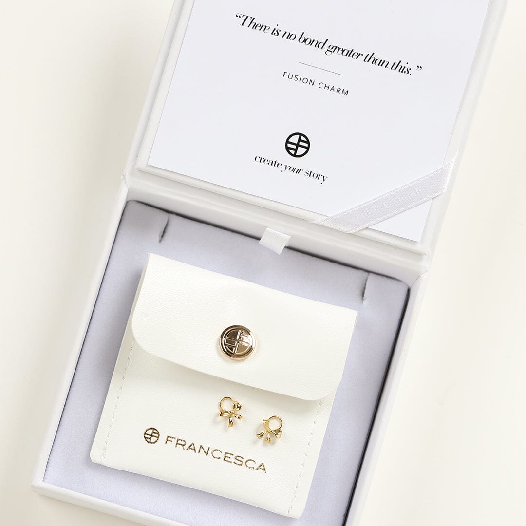 A set of two gold hoop charms with a bow design, in white box