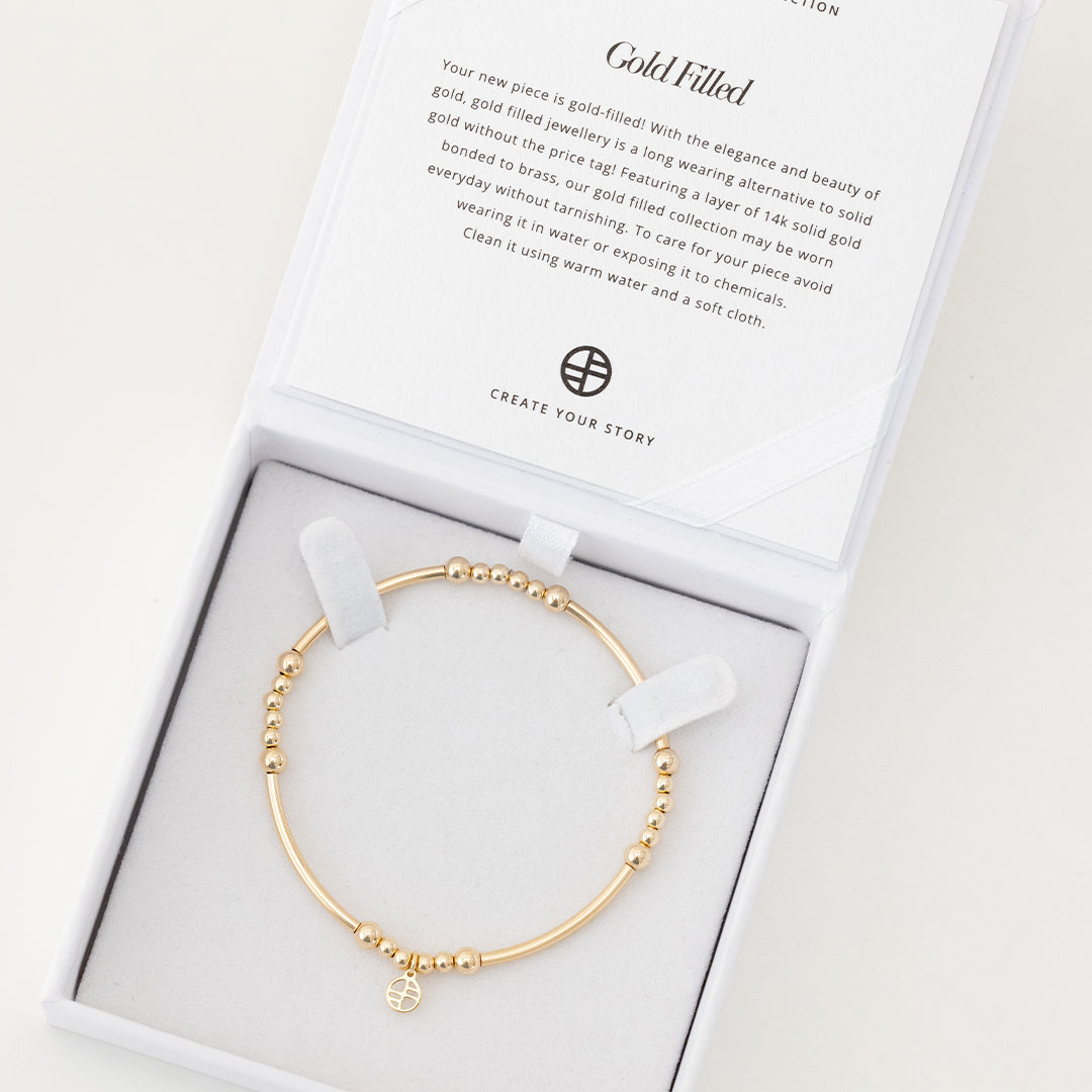 A gold-tone bracelet with spherical beads and a Francesca logo, displayed in a white box