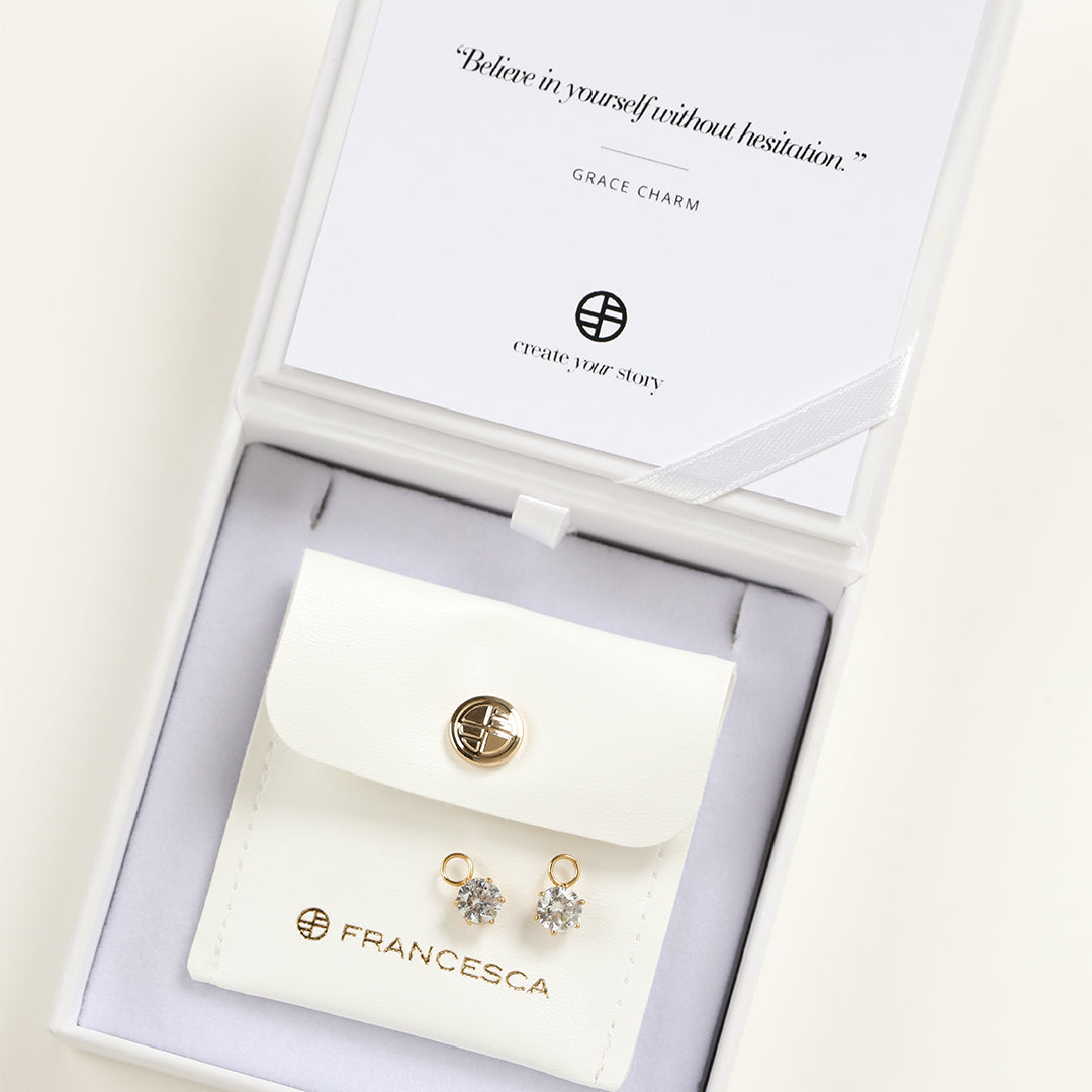 A set of two hoop charms with gold metal tone, designed to be attached to earrings, displayed in a white box