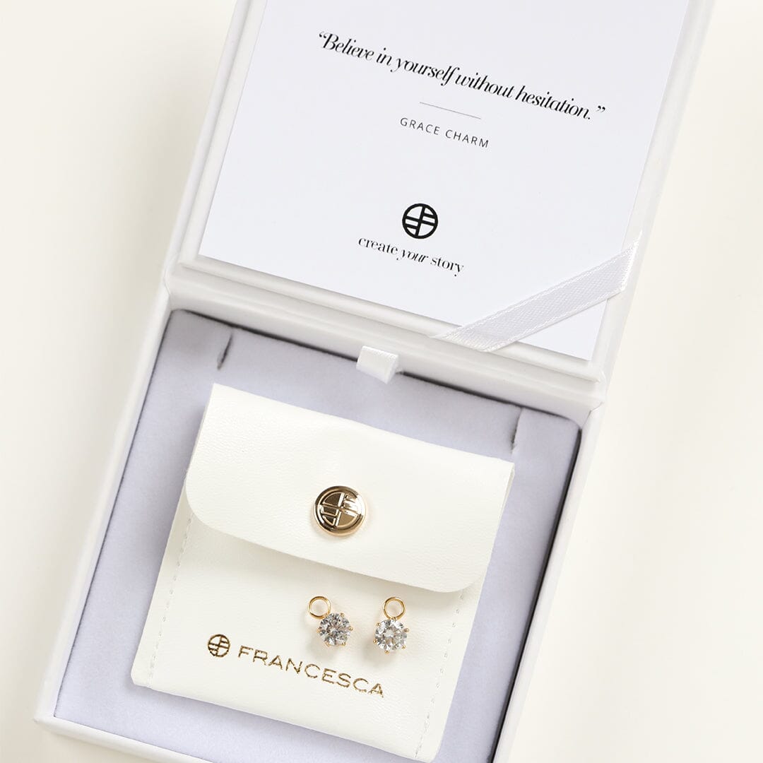 A set of two hoop charms with gold metal tone, designed to be attached to earrings, displayed in a white box