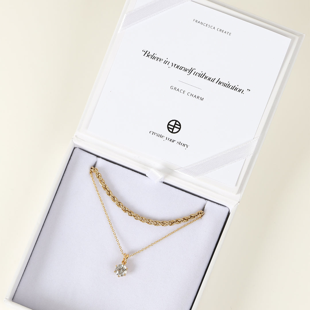 Round, gold, cubic zirconia charm on gold chain, displayed in white box