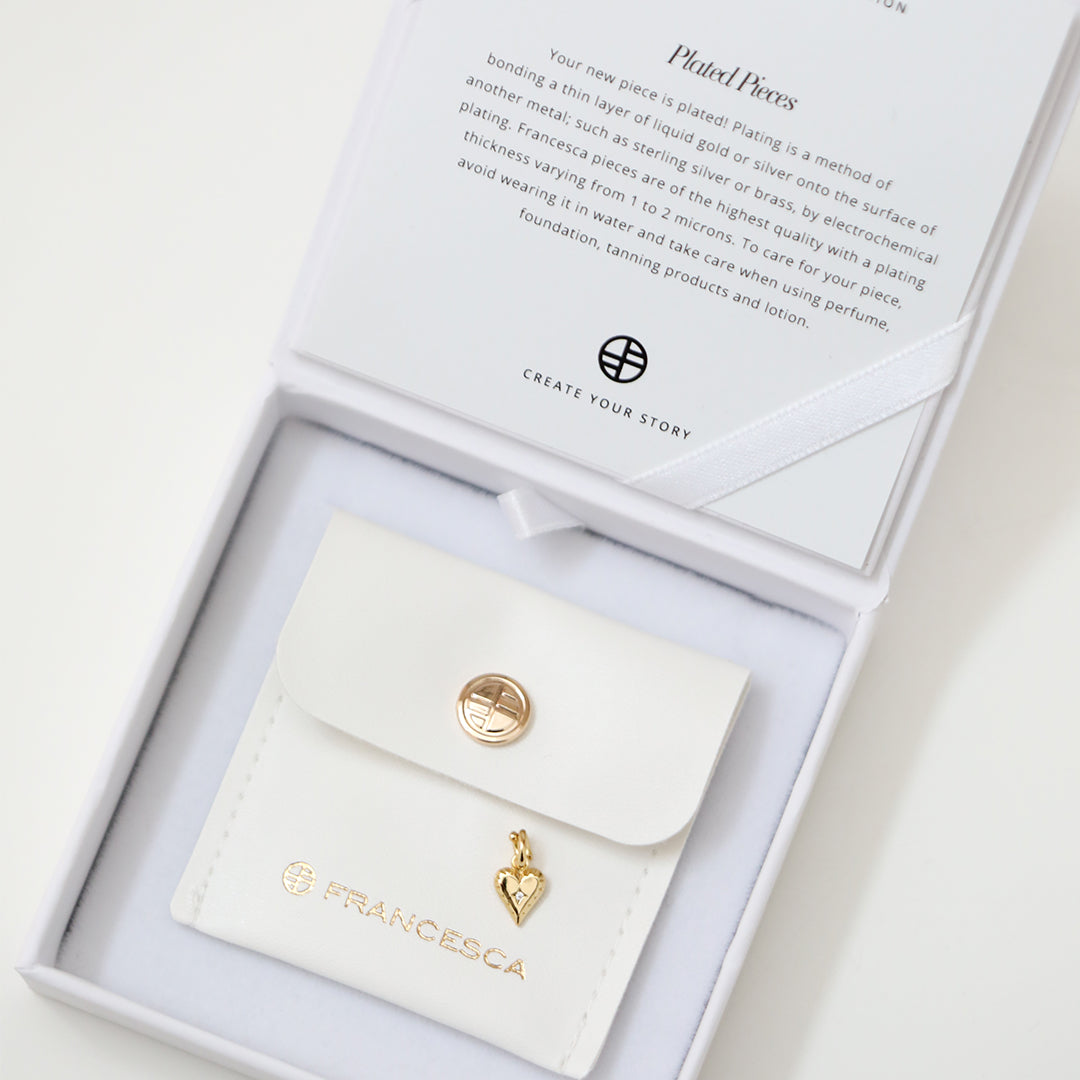 A delicate heart-shaped charm in gold metal tone in white box
