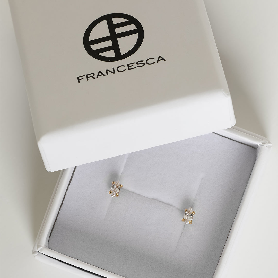 A pair of stud earrings with clear cubic zirconia set in gold metal, presented in a white box.