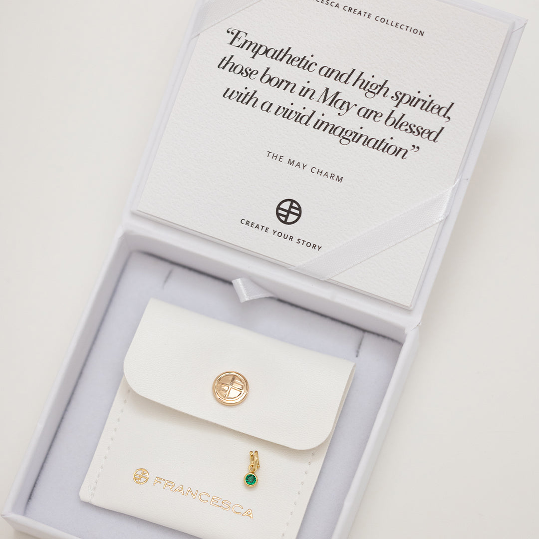 A gold, round bezel set emerald cubic zirconia reflects May birthstone colour in white box