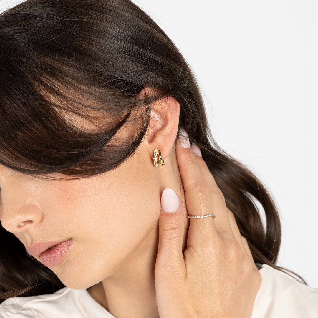 close up shot of gold double huggies with cubic zirconias worn in ear