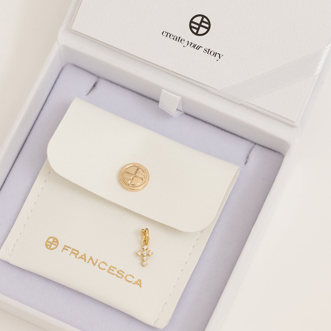 A petite gold cross charm with cubic zirconia in white box