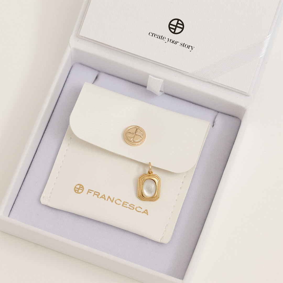 A gold-colored pendant with an oval mother-of-pearl stone in the center, in white box