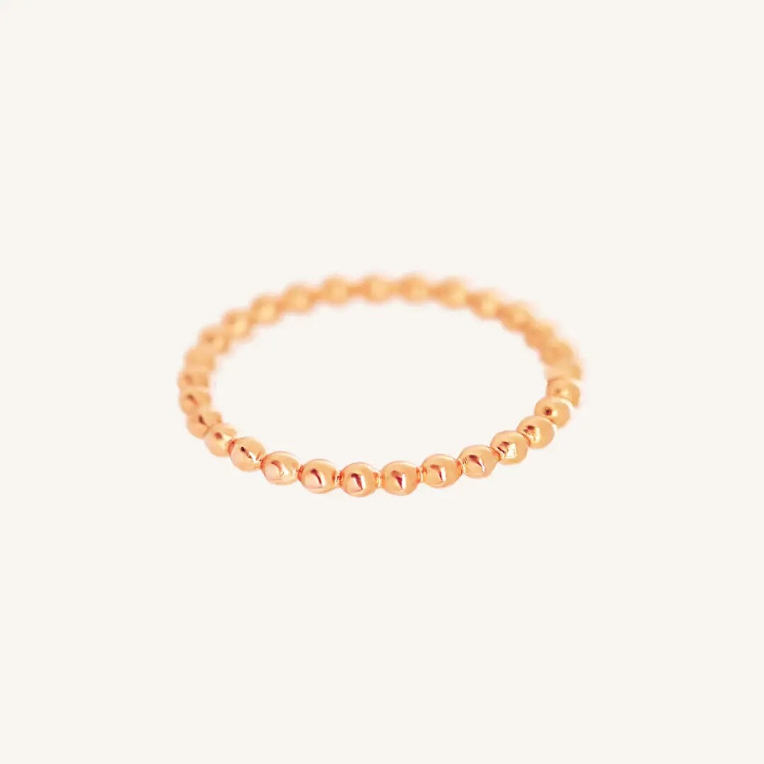 A rose gold coloured stacking ring with a simple, elegant design featuring small, uniform beads around its circumference.
