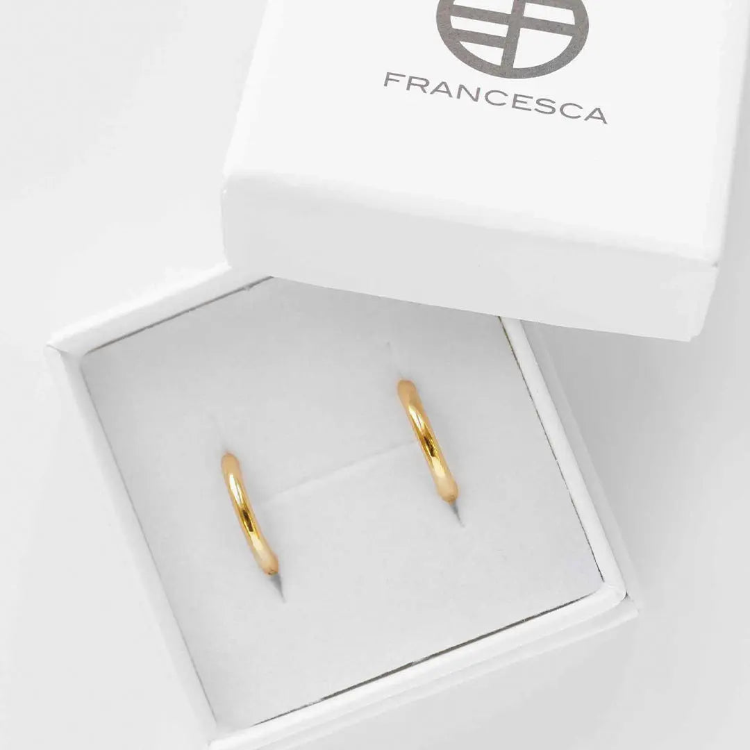 A pair of gold-colored hoop earrings in white box