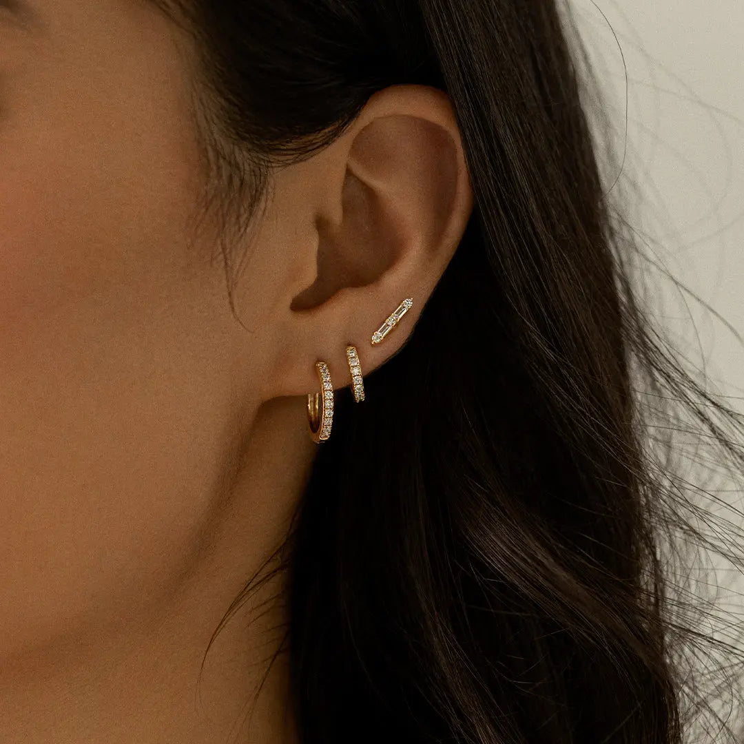 Small gold huggies, with cubic zirconias wrapped around, worn in models ear