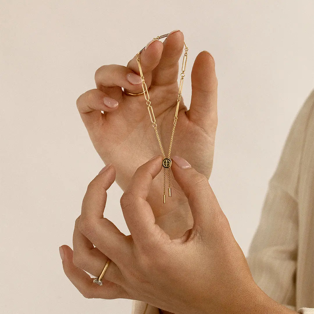 A gold chain bracelet with an adjustable fastening design and an engraveable panel.