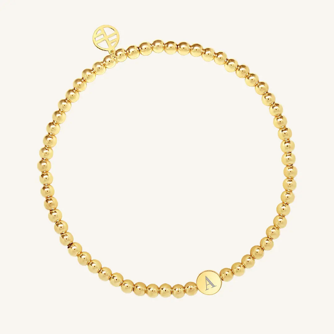 A gold bracelet with a beaded design and an engraveable bead