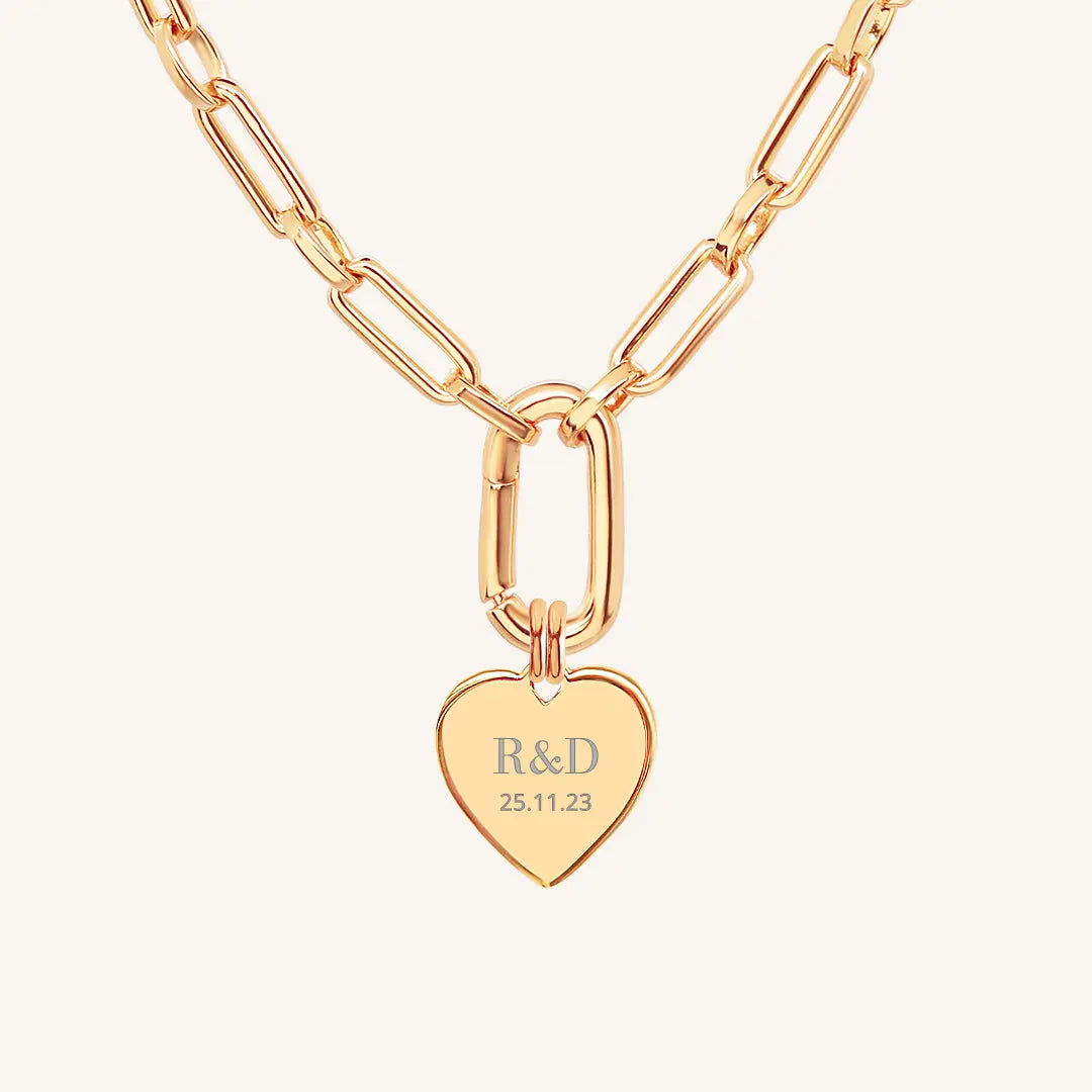 A rose heart-shaped necklace with a chain, featuring an engraved monogram initials and a date on the front.
