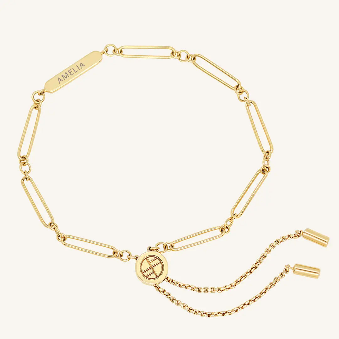 A gold chain bracelet with an adjustable fastening design and an engraveable panel.