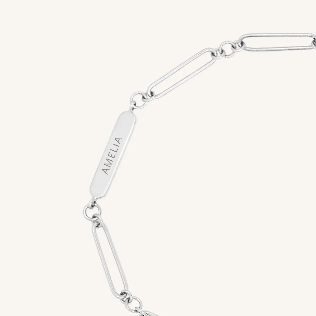 A silver chain bracelet with an adjustable fastening design and an engraveable panel.