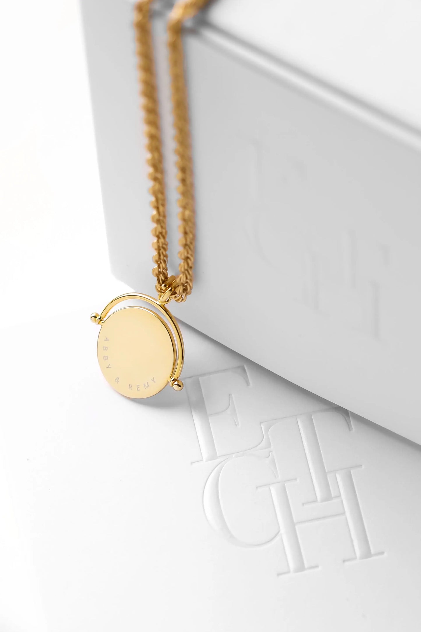 A gold-coloured, engraved pendant with, featuring a spinning mechanism, on chain