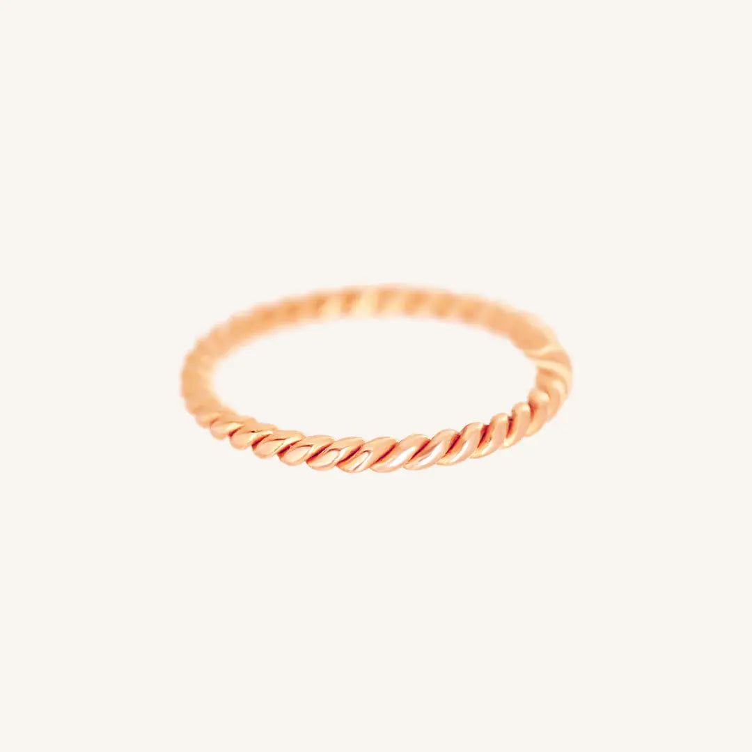 A rose gold-coloured stacking ring with a twisted design, displayed against a white background.